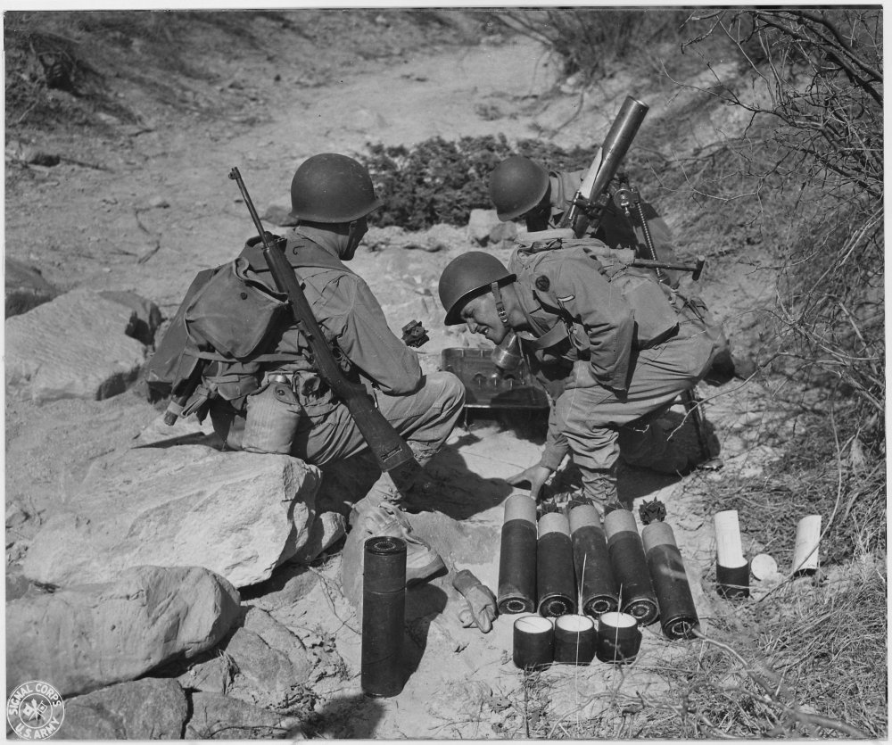 Can you identify the firearms slung over the shoulder of the soldier on the left?