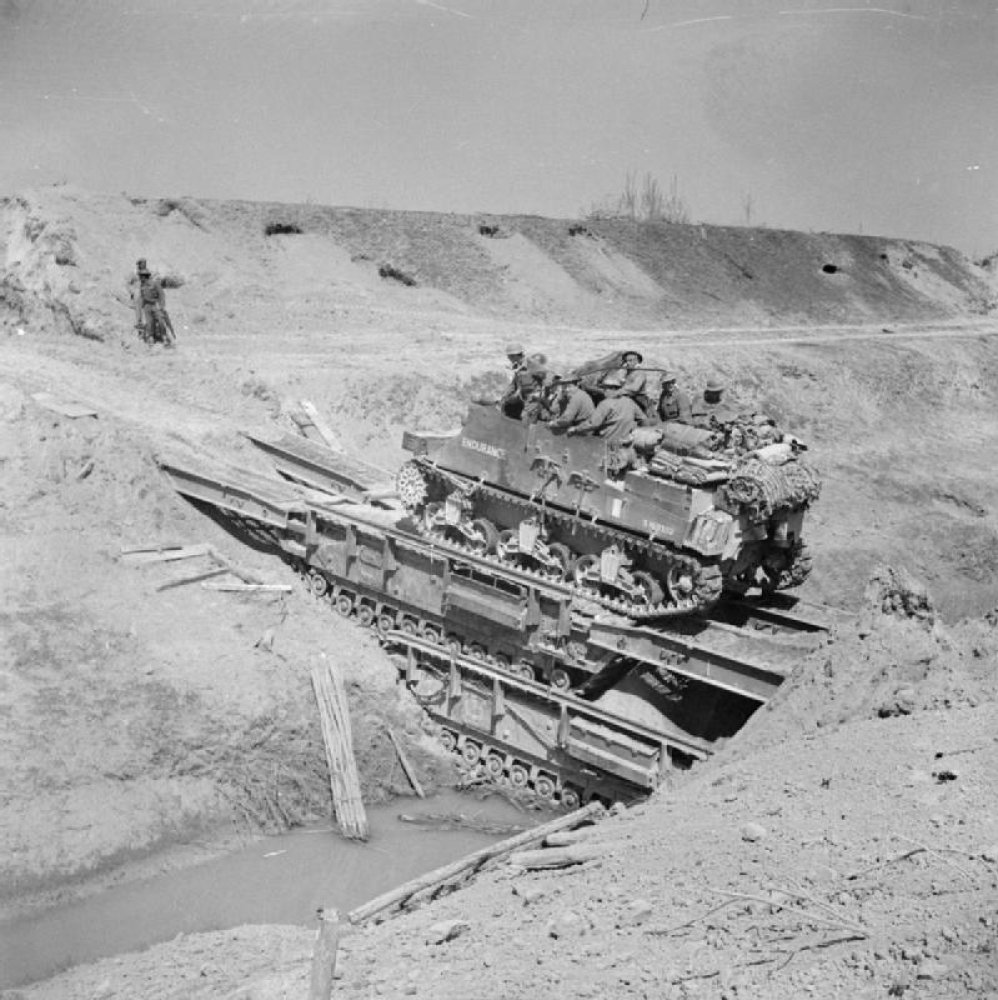 The two bottom vehicles in the photo, the ones turned into a makeshift bridge, are turretless Churchill tanks developed for the famous Hobart’s Funnies. Do you know their designation?